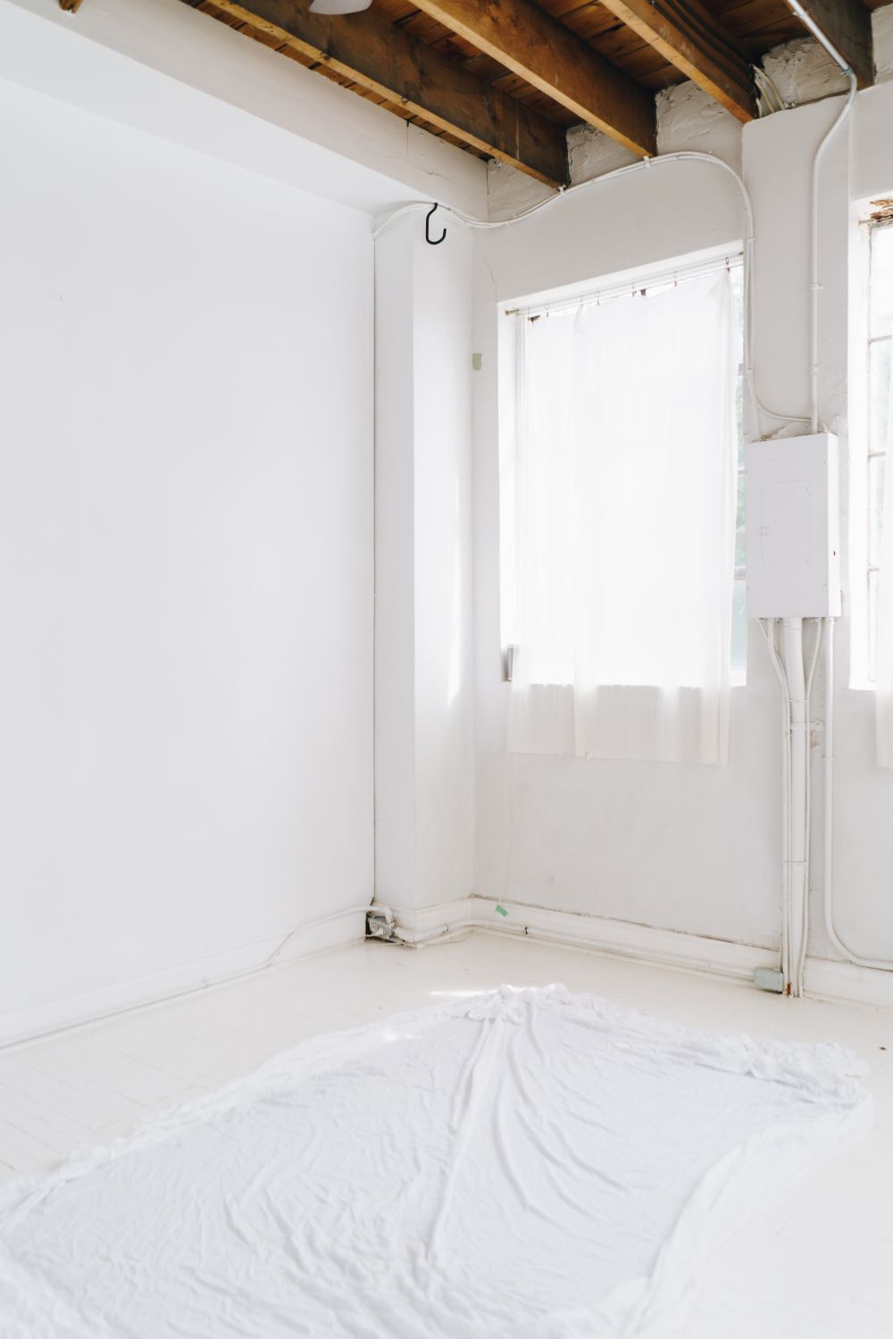 A bright room with white walls and exposed ceiling beams during renovation